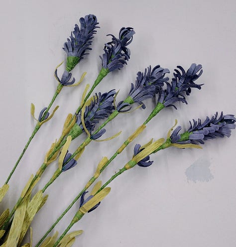 Artistic flowers made of paper, blue cornflowers, lilac peony and purple lavender, all coloured using red cabbage.