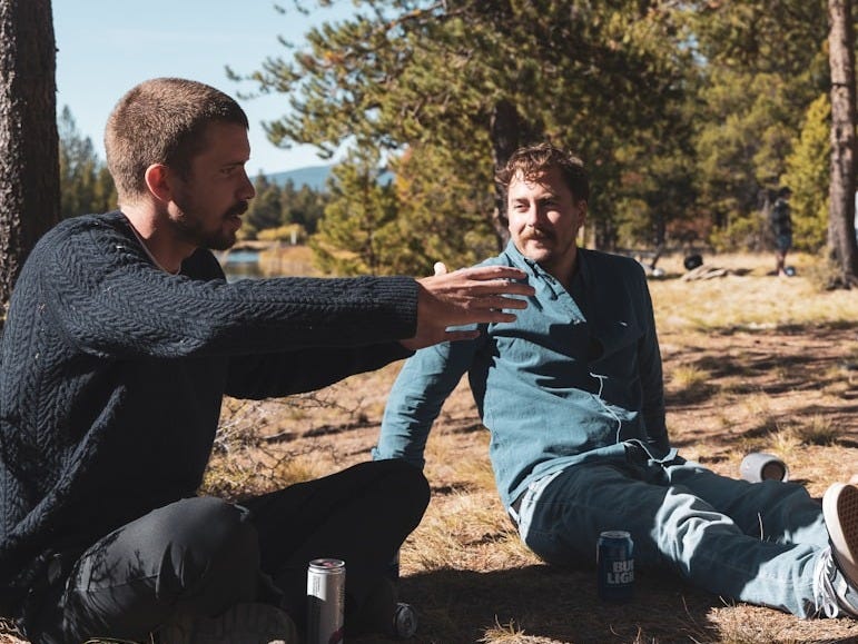 three men sitting on the ground in the woods three men sitting on the ground in the woods