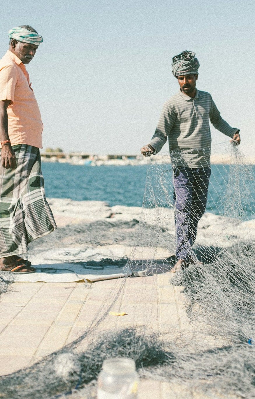 man holding fish net near sea man holding fish net near sea