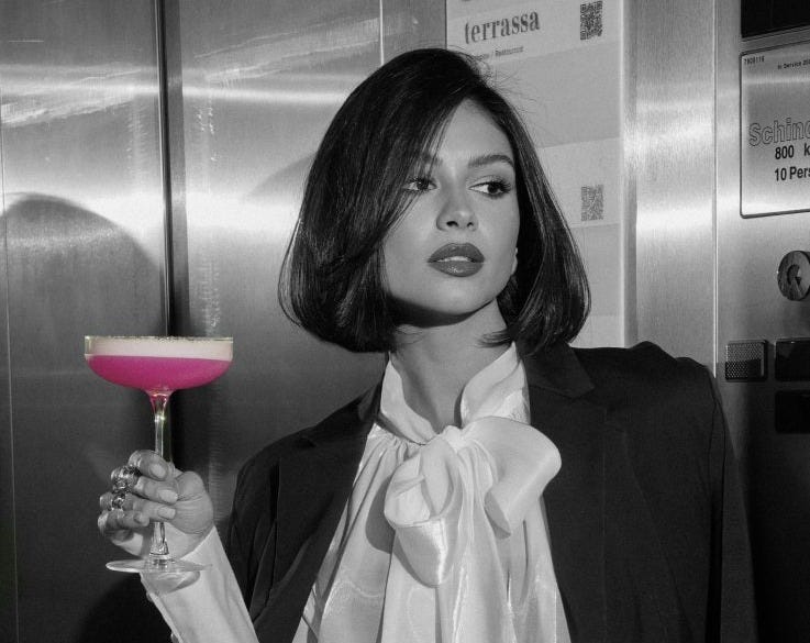 Kvinna i en hiss som håller i en rosa drink Kvinna i en hiss som håller i en rosa drink