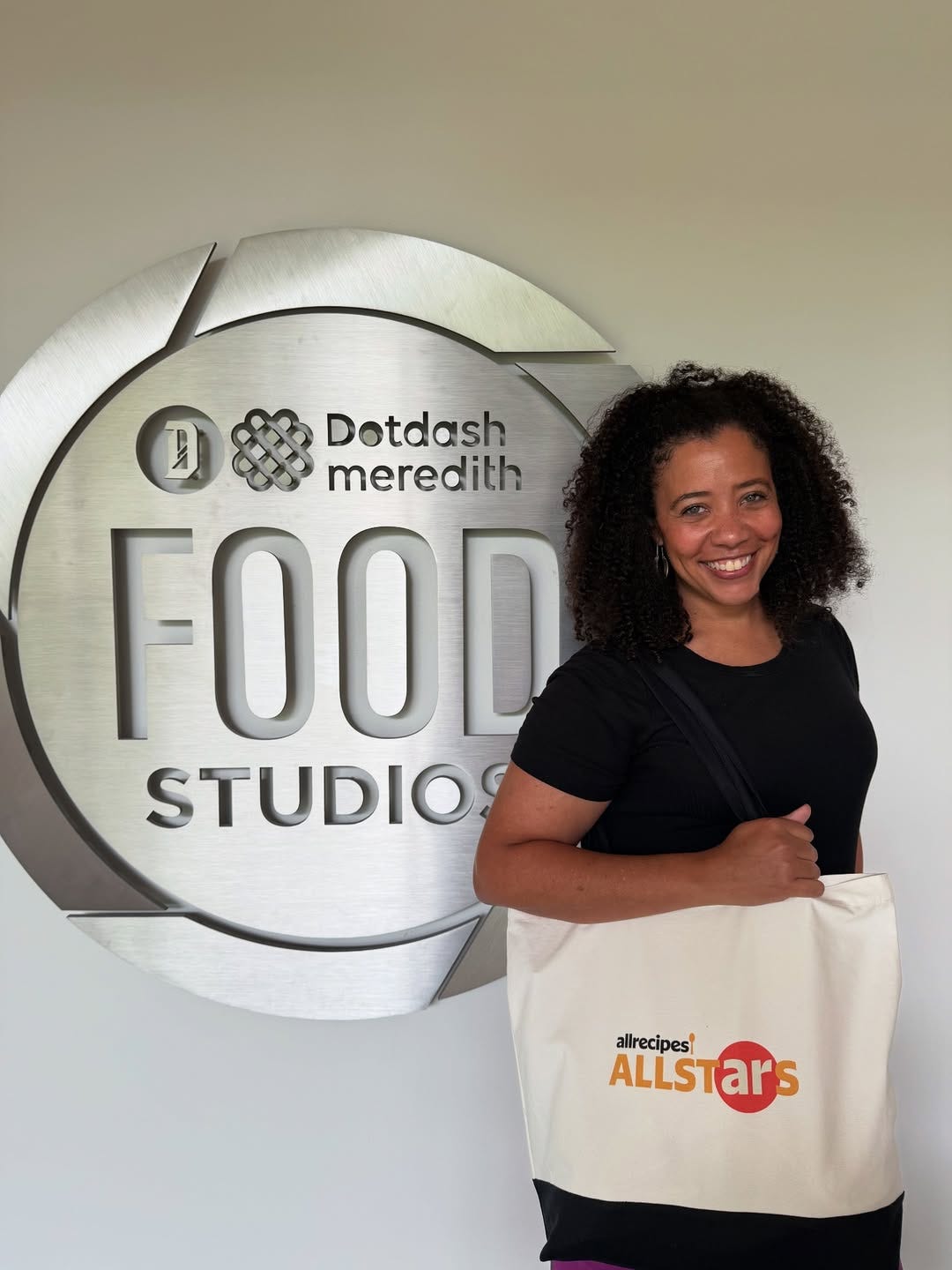 Jessica in front of the Dotdash Meredith Food Studio sign