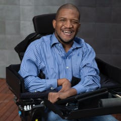 Lateef McLeod, a black man in a wheelchair, smiling.