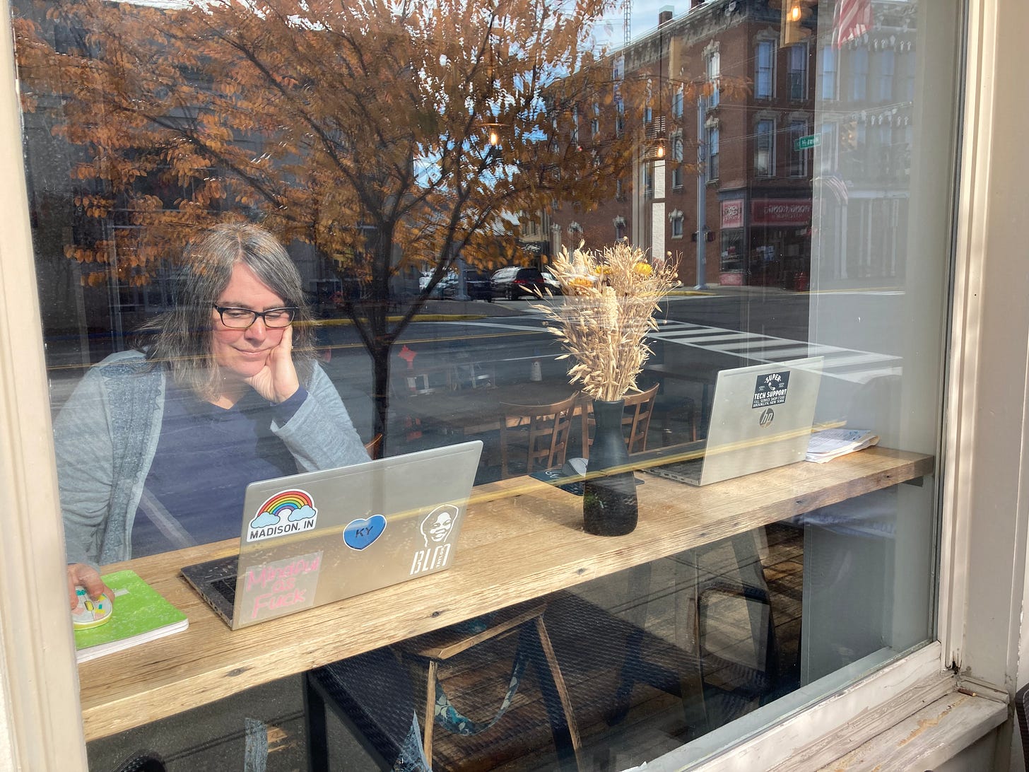 Robyn in the window of a coffee shop pretending like she's very engrossed in her computer (she's not)