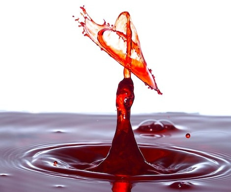 Close-up of red water splashing against white background