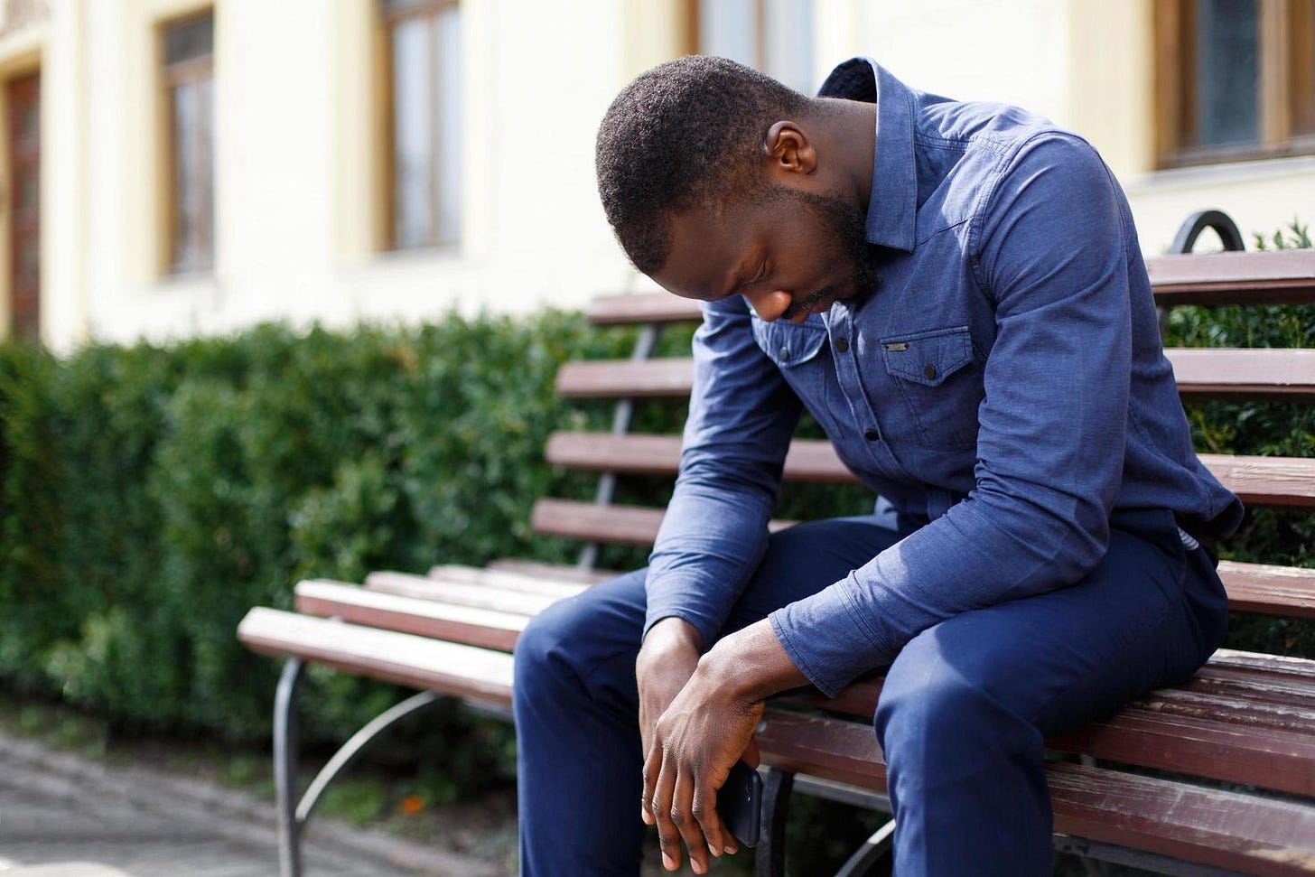 Tired man sits on the bench outside 1435504 Stock Photo at Vecteezy