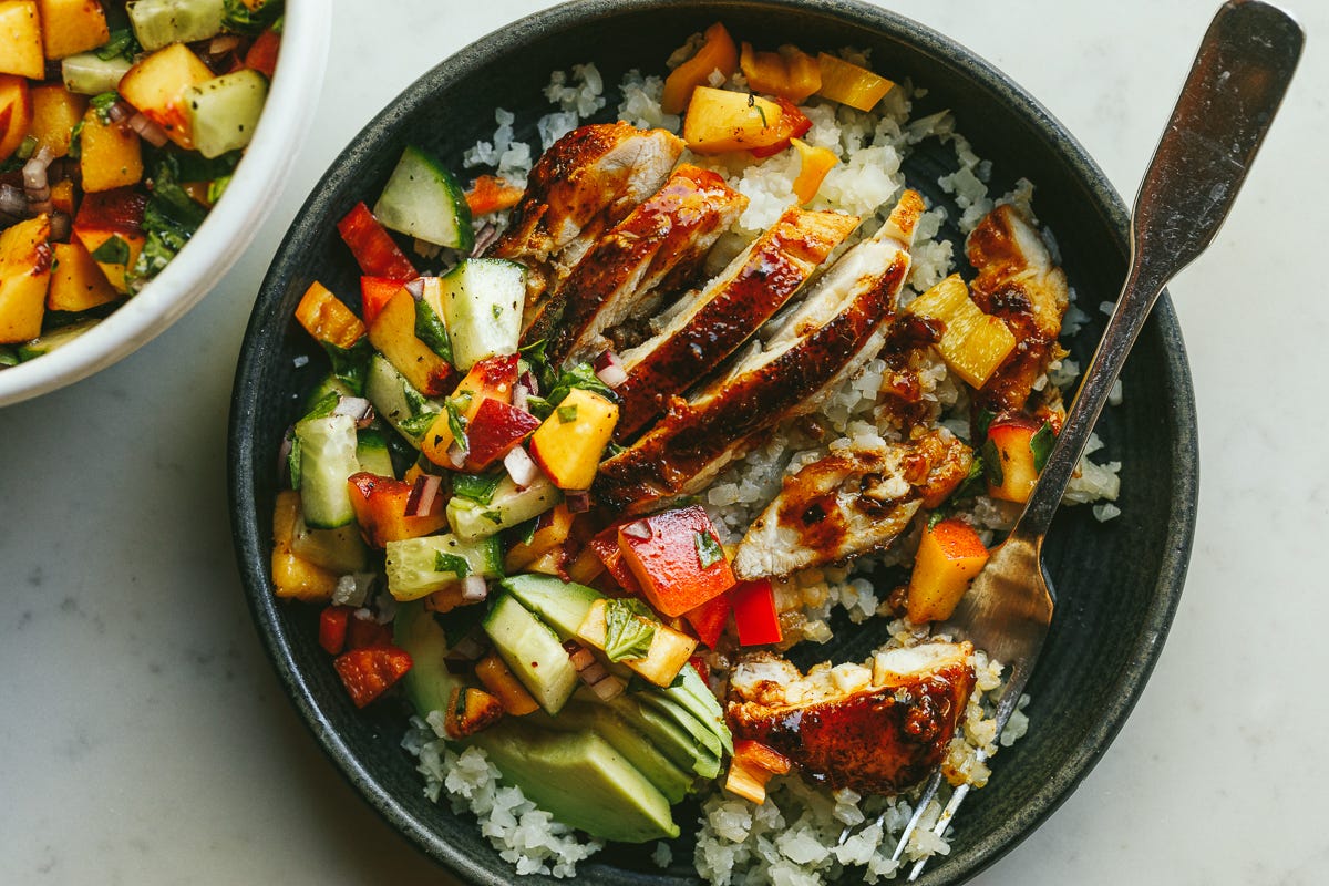 hot honey chicken bowls with peach salsa in a black dish. 