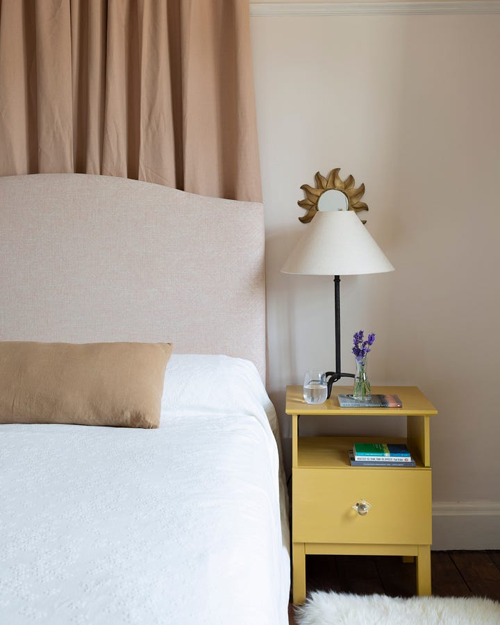 wardrobes, bed with pink curtain above and yellow bedside table with lamp on