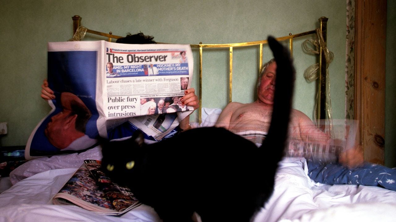 A couple reading the Sunday newspapers in bed