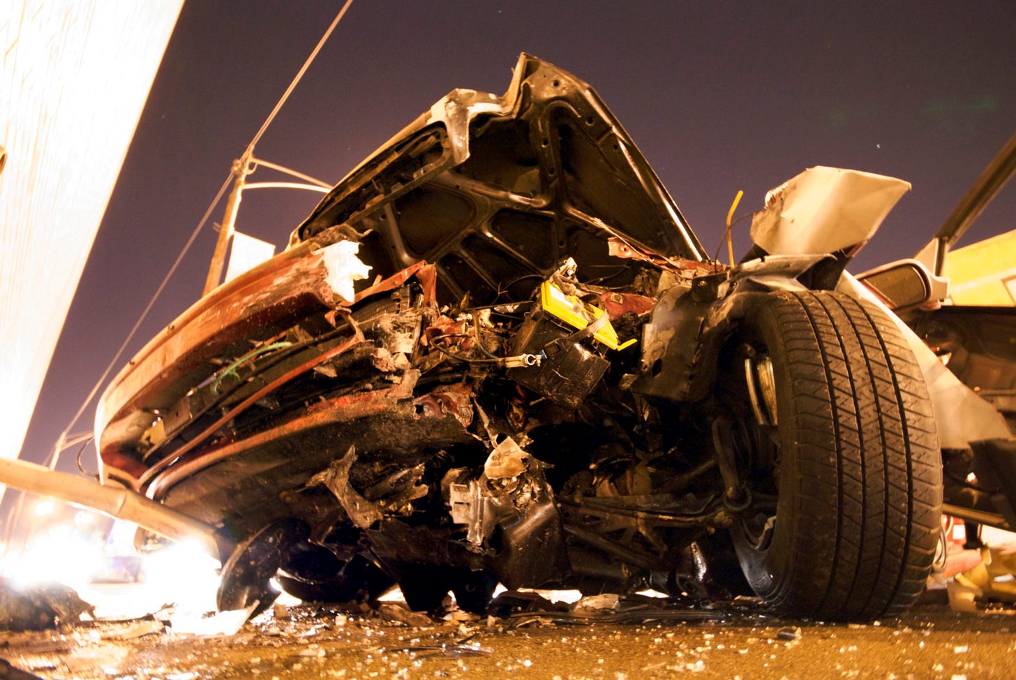 A very badly damaged car with a wheel splayed at a funky undrivable angle to the side