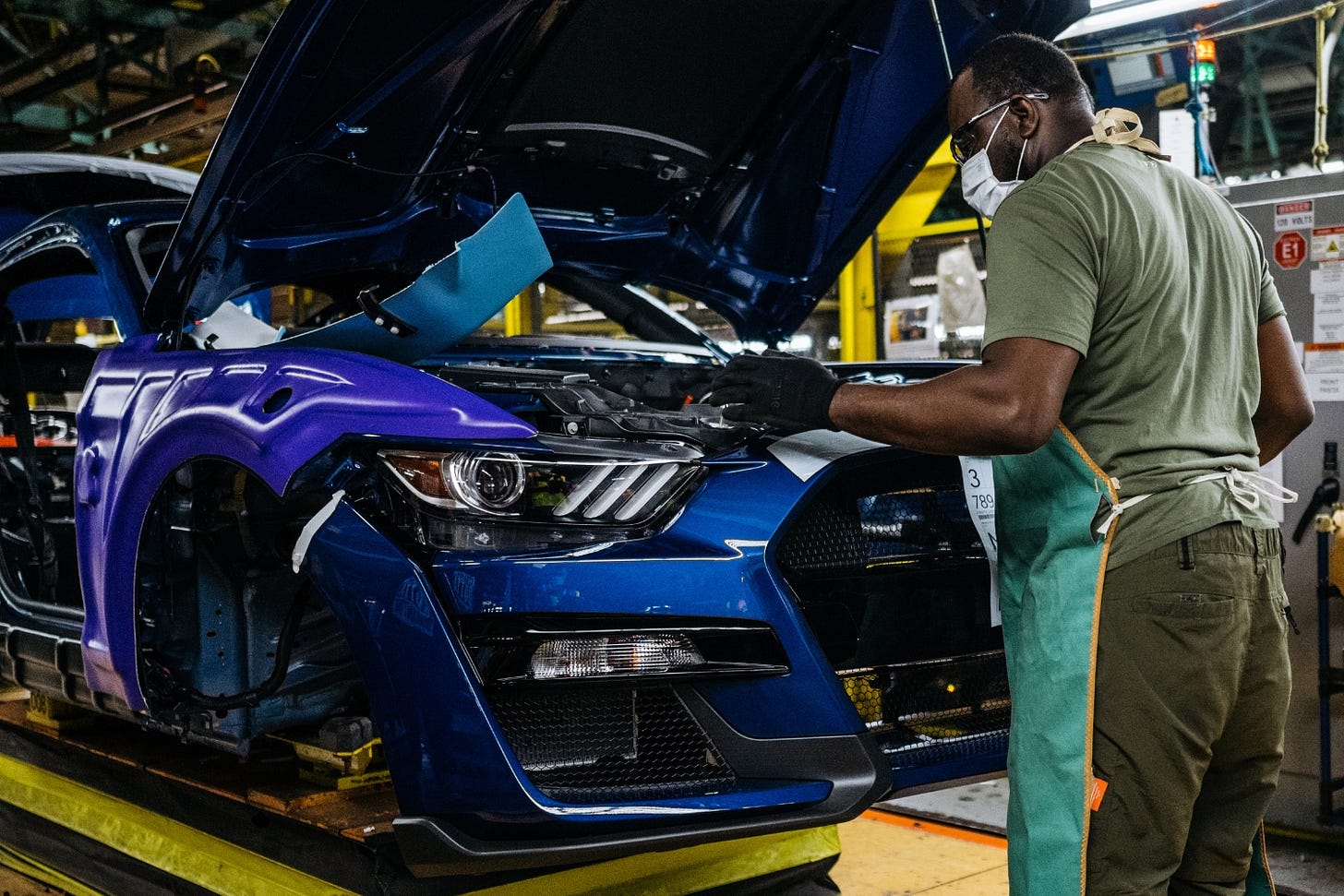 A UAW worker builds a blue Ford Mustang on an assembly line in Flat Rock, Michigan.