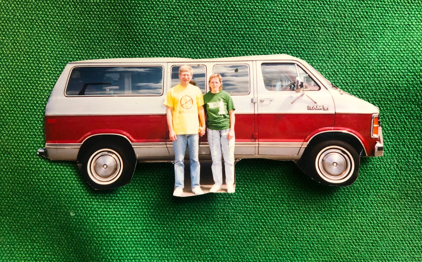 a man and a woman standing in front of a silver and maroon van