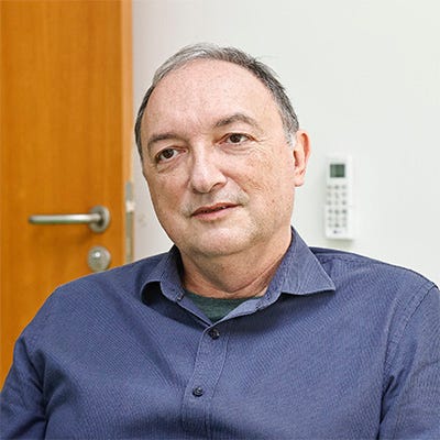 Homem branco com cabelos grisalhos cortados bem curtos, vestindo uma camisa azul Homem branco com cabelos grisalhos cortados bem curtos, vestindo uma camisa azul