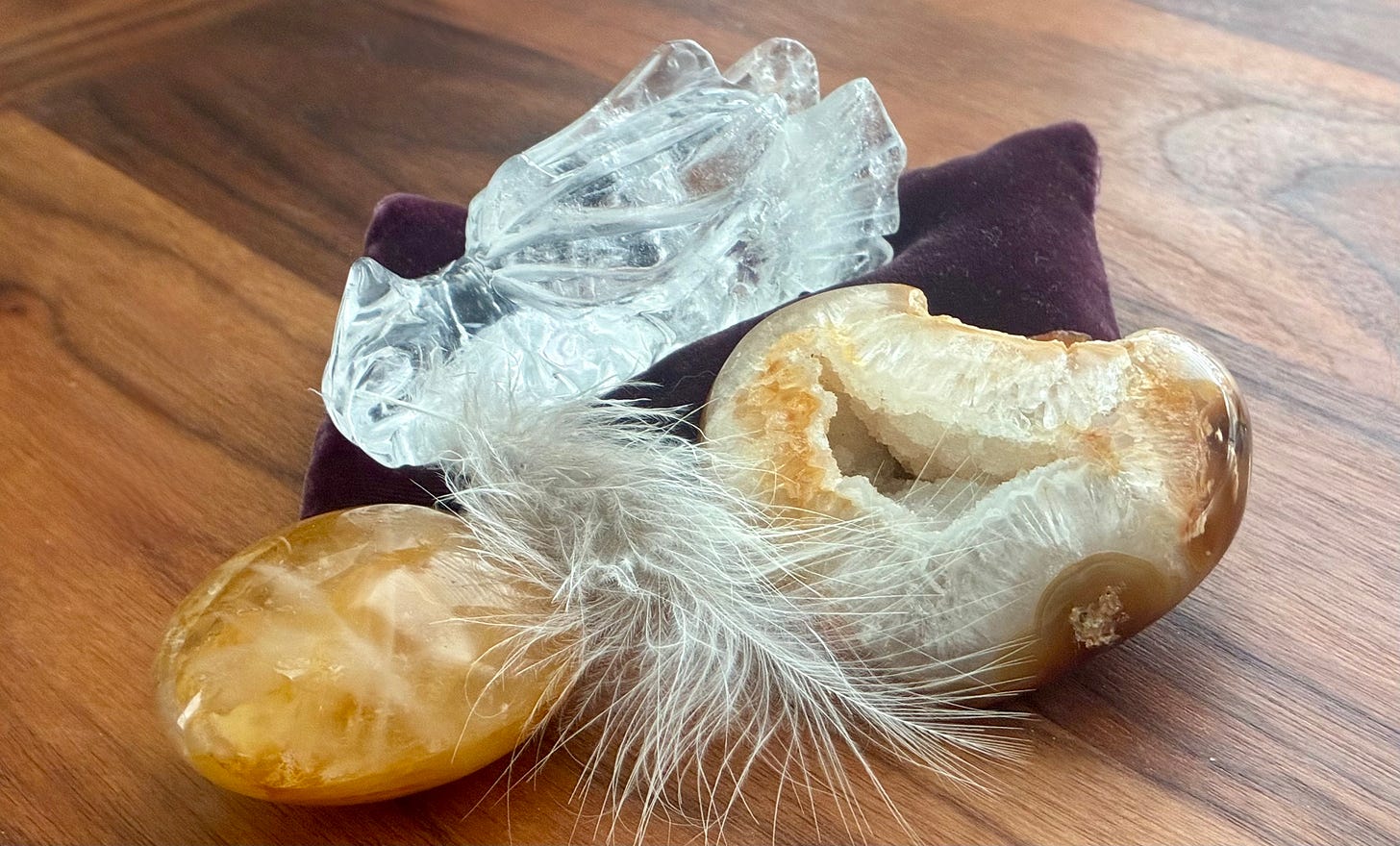 Golden crystals and a clear quartz dragon head resting on a wooden table. 