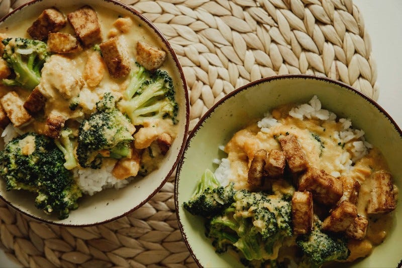 creamy tofu and broccoli rice bowls on a woven place mat