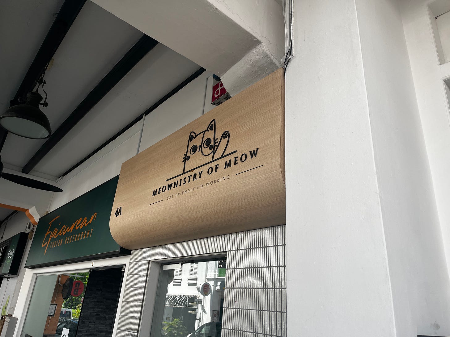 Wooden sign above a shop's door. The sign reads Meownistry of Meow, cat-friendly co-working.