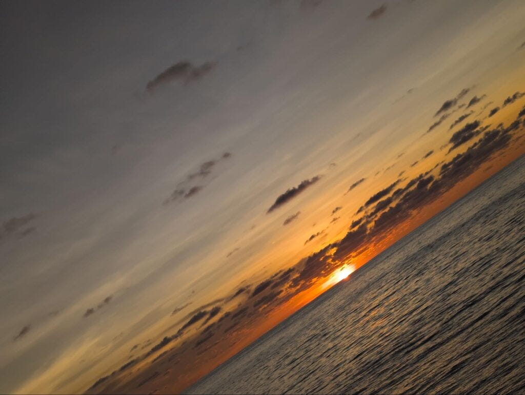 Dramatic ocean sunset with orange sky clouds reflecting on rippling water surface Dramatic ocean sunset with orange sky clouds reflecting on rippling water surface
