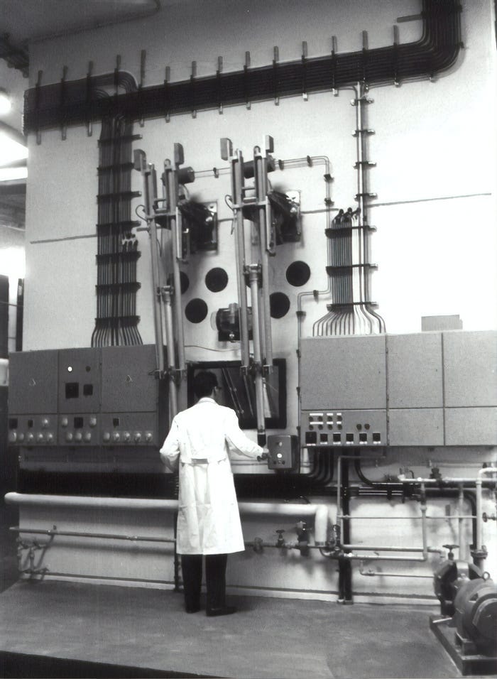 In an old black and white photograph, a worker in a lab coat manages the switchboard at a nuclear power plant. In an old black and white photograph, a worker in a lab coat manages the switchboard at a nuclear power plant.