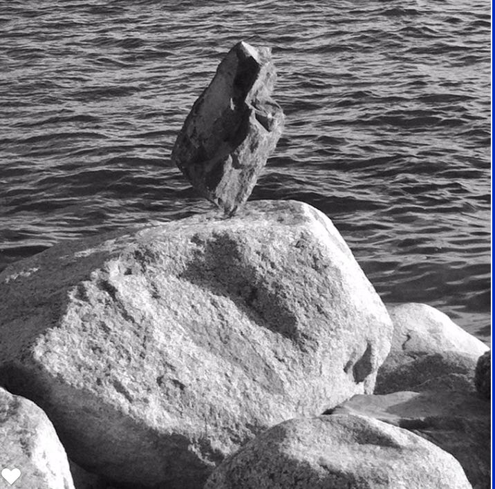 a rock balanced on a point on top of another rock