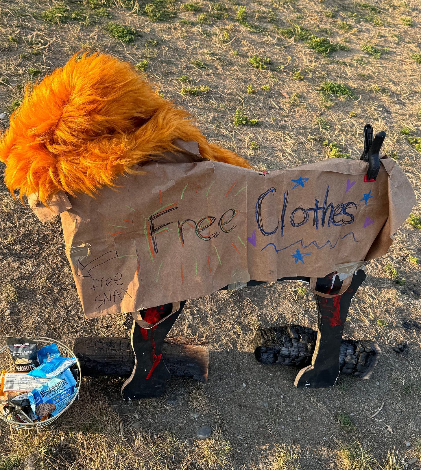 sign that says Free Clothes and in smaller text "free snax" with a bowl of snacks on the ground