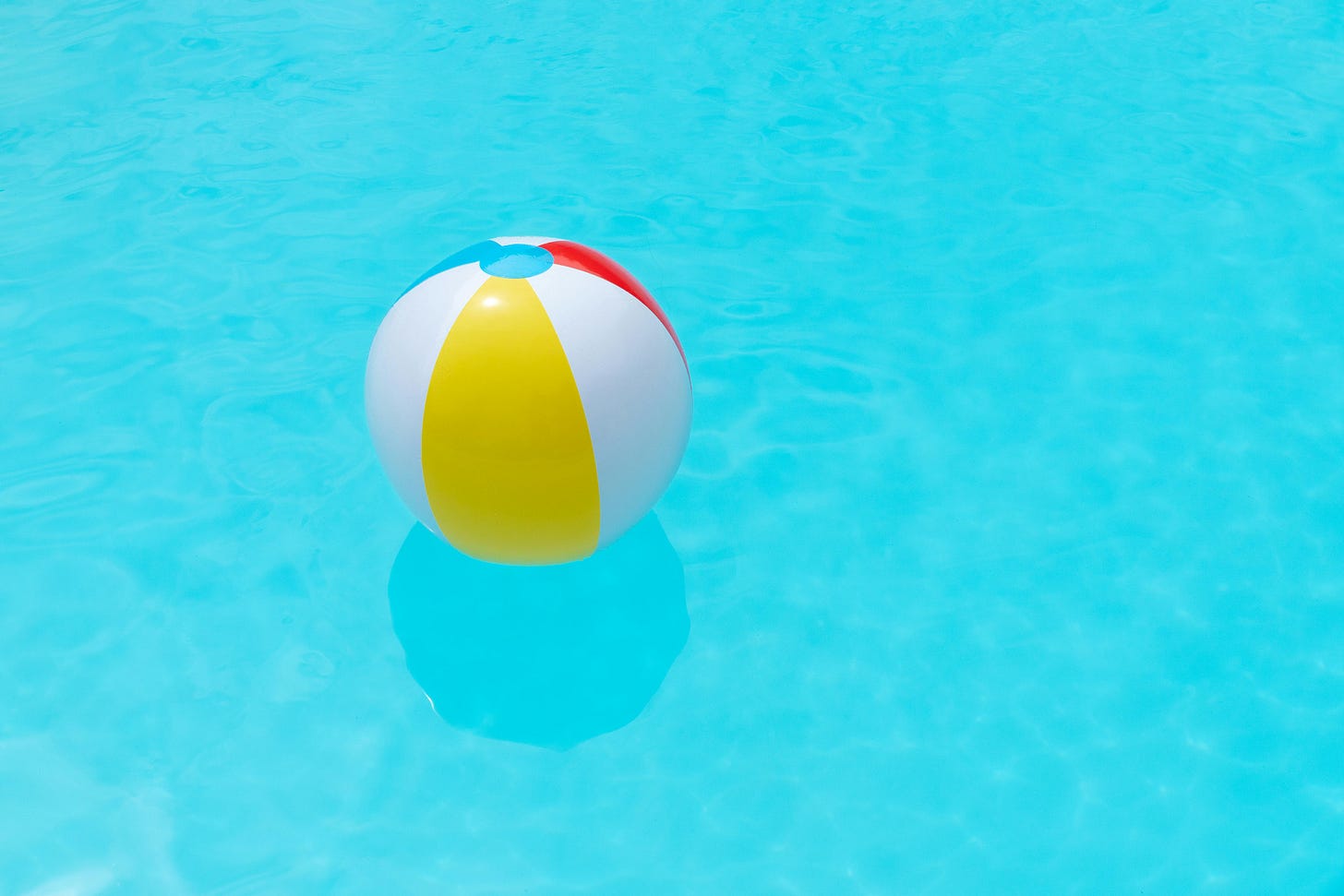Beach ball in very blue pool.