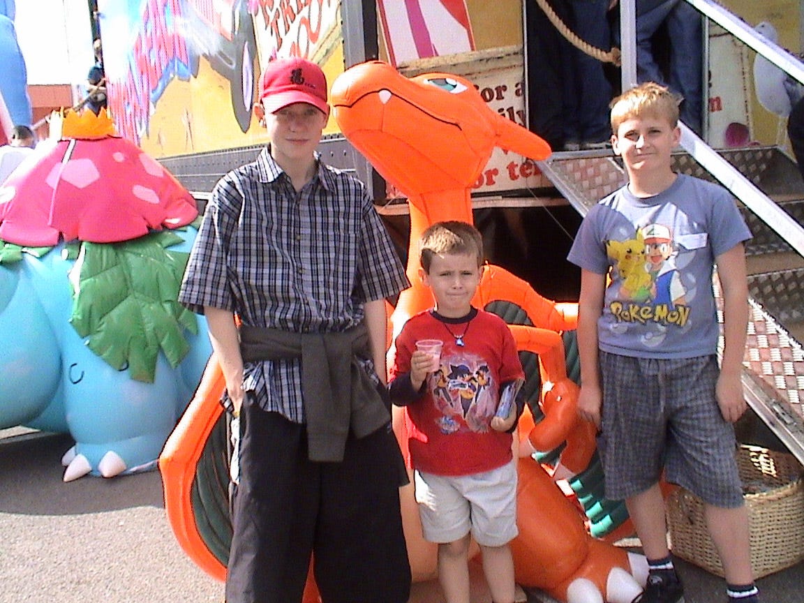 A photograph of Luke, his best friend, and his brother at one of the stops the tour took on October 1st, 2004, featuring an inflatable Charizard in the background A photograph of Luke, his best friend, and his brother at one of the stops the tour took on October 1st, 2004, featuring an inflatable Charizard in the background