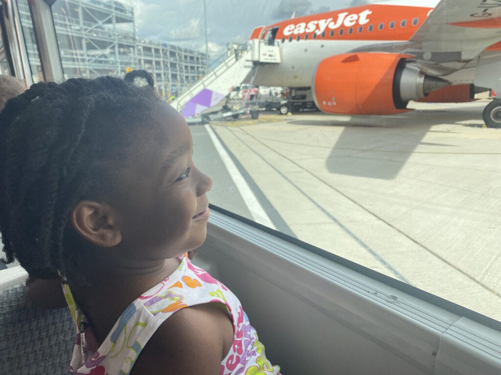 Rainbow looking out the window at an EasyJet plane