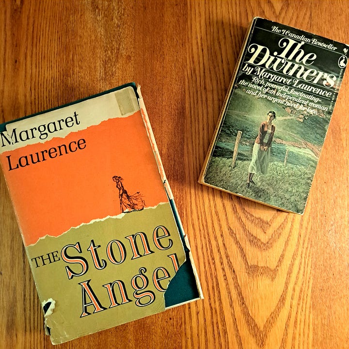 photo of an old hardcover book, The Stone Angel, and an old paper back of Laurence's The Diviners on a wooden table, and an image of Margaret Atwood's Susanna Moodie poetry book on black fabric