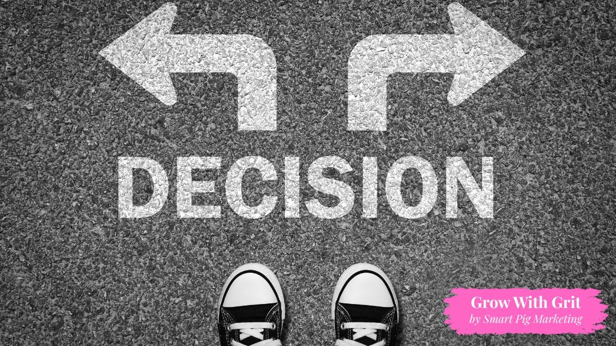 Overhead view of a person standing at a crossroads painted on pavement with arrows pointing in opposite directions above the word "Decision," symbolizing the challenge of choosing between different paths. Grow With Grit by Smart Pig Marketing branding appears in the lower right corner.