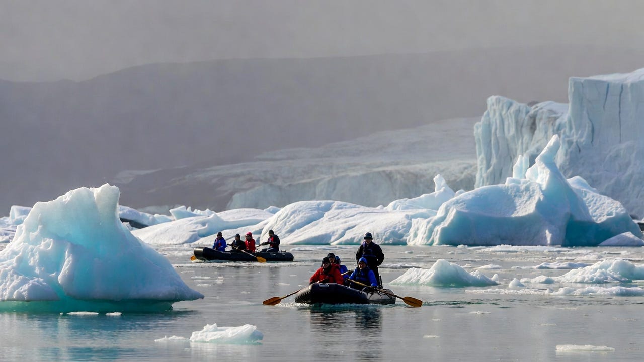 Generate me a high-quality image of people in boats exploring the Arctic in rubber boats, just a couple.