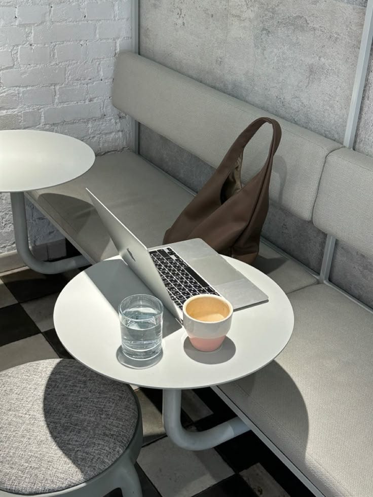 This may contain: a laptop computer sitting on top of a white table next to a cup of coffee