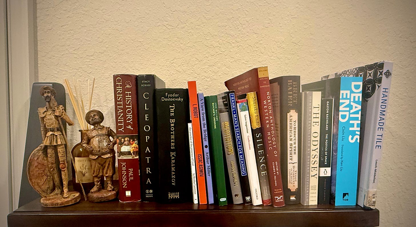 A shelf with books and Don Quixote statues