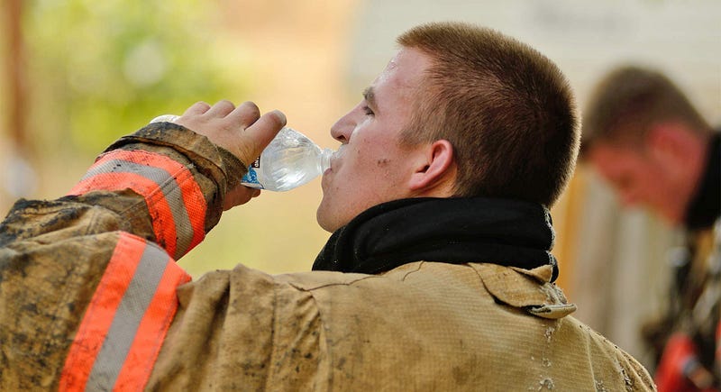 A firefighter drinks a bottle of water A firefighter drinks a bottle of water