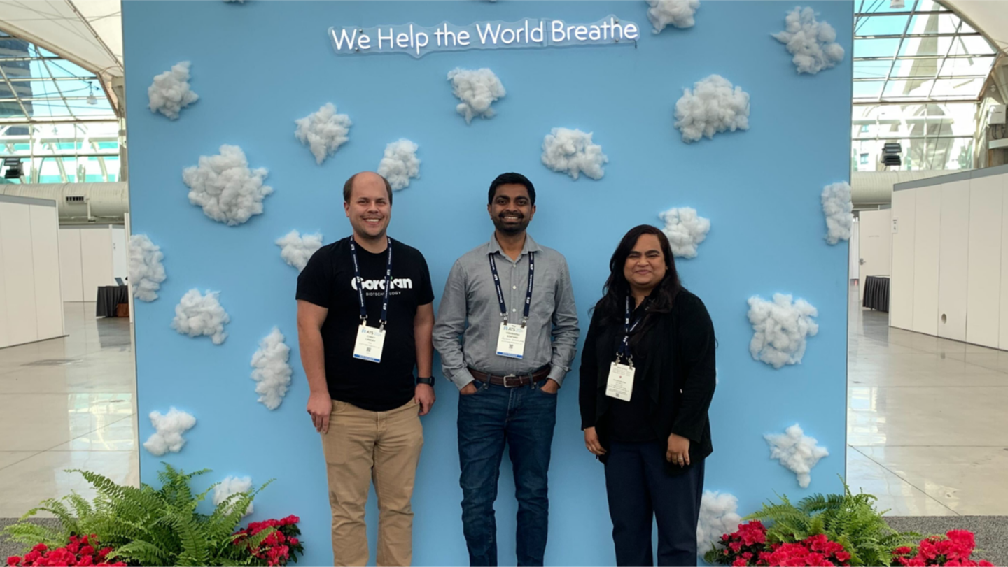 three people standing in front of a banner with clouds
