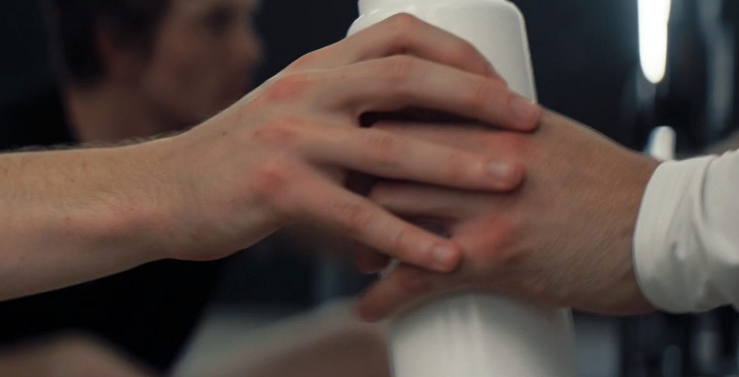 Heated Rivalry close up of bottle scene where Ilya hands Shane his bottle and their fingers touch briefly Heated Rivalry close up of bottle scene where Ilya hands Shane his bottle and their fingers touch briefly