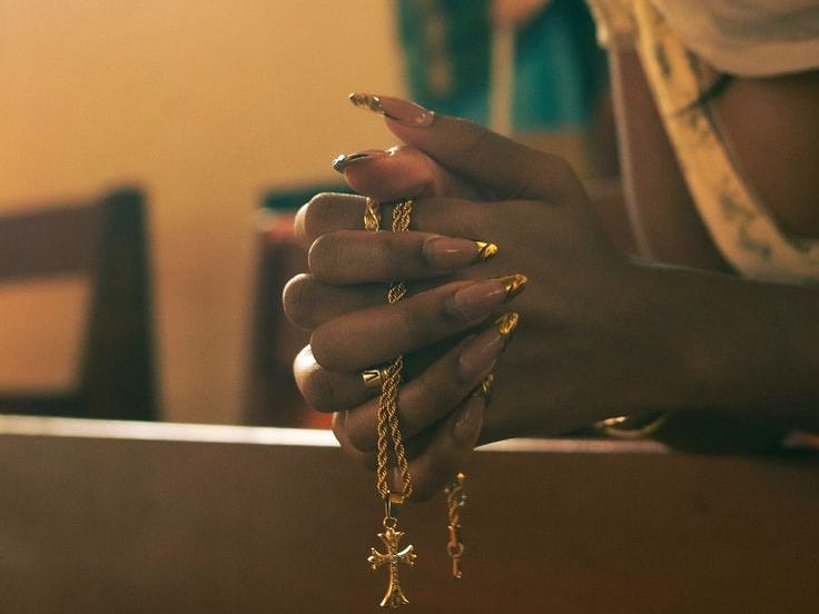 This may contain: a woman with her hands on the edge of a table holding some gold chain bracelets