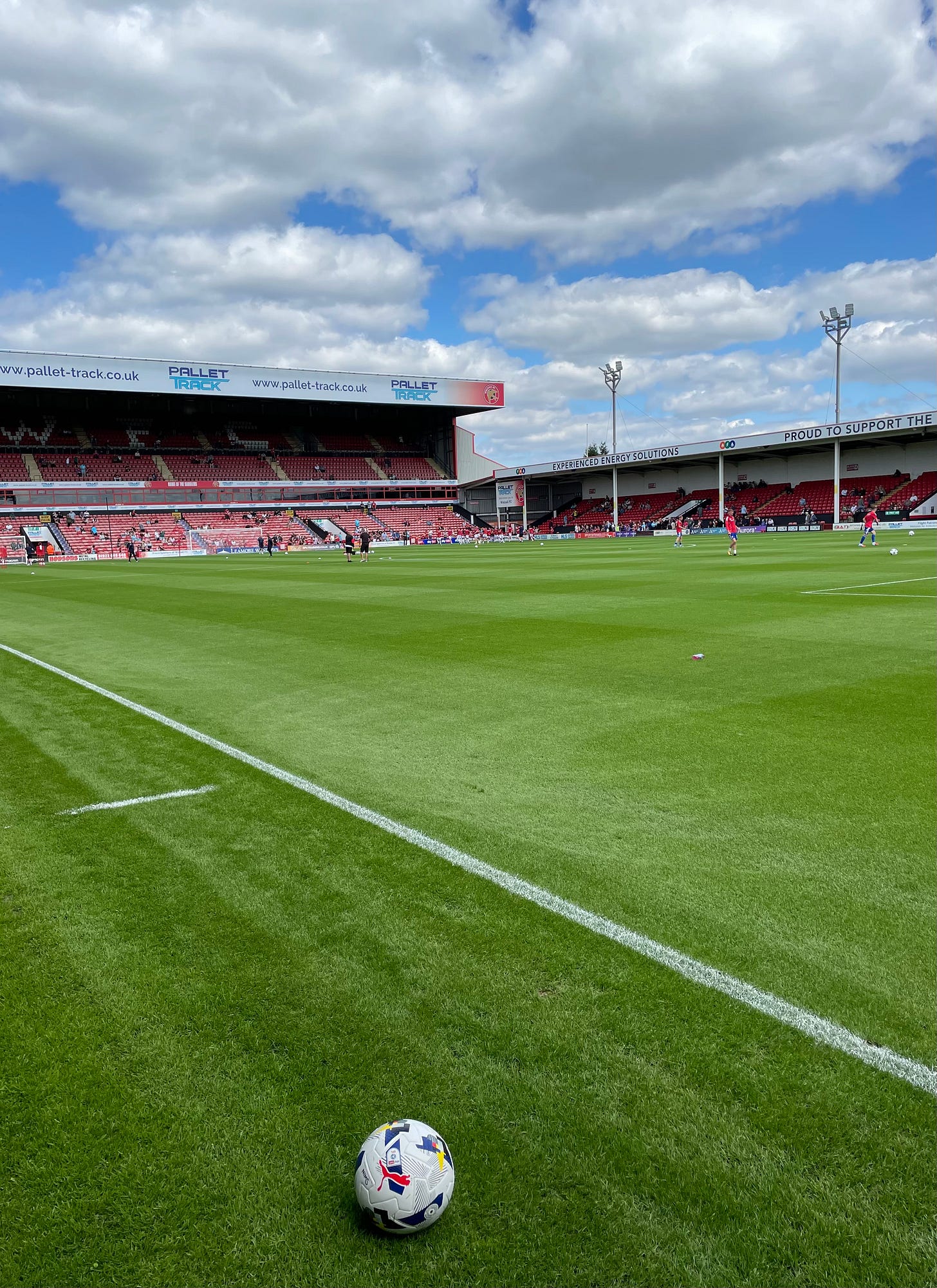 The pitch at Bescot stadium in the sunshine. A football is placed in the foreground, before the match kicks off.