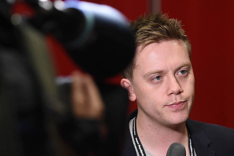 A man with a microphone in front of a TV camera A man with a microphone in front of a TV camera