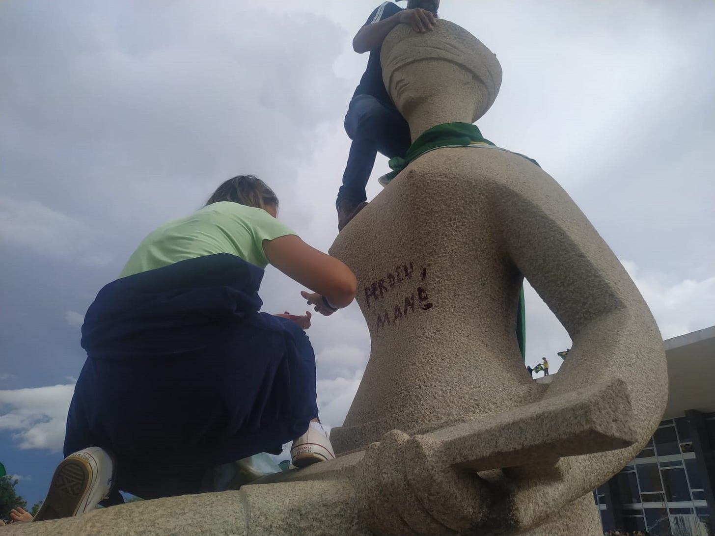 Cabeleireira Débora Rodrigues dos Santos pichando estátua "A Justiça", em frente ao STF, com batom durante atos golpistas de 8 de janeiro de 2023
