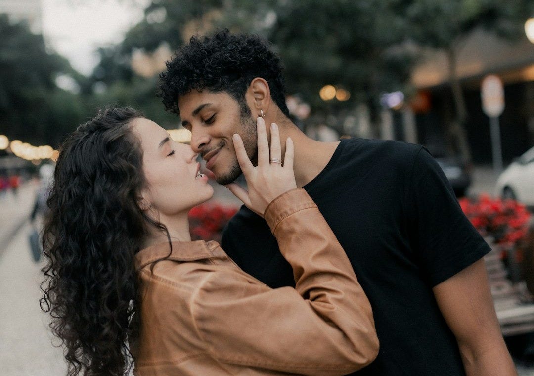 A couple kisses amidst a cityscape.
