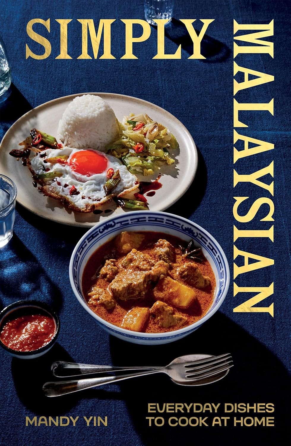 Navy cover of Simply malaysian with text in gold and two bowls of food.