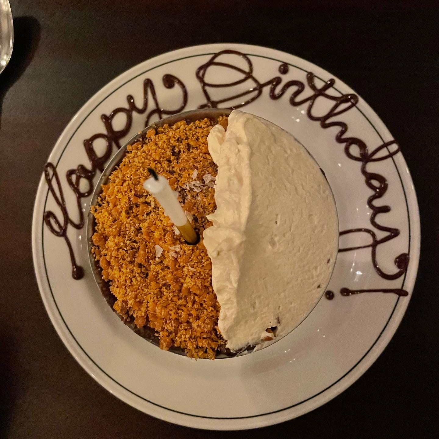 A dish of pudding with "happy birthday" written around it on a plate in what I hope is chocolate sauce.
