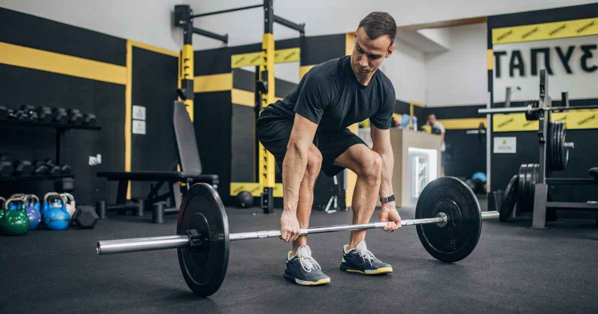 Man in the gym about to deadlift a barbell off the floor
