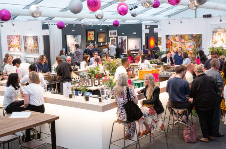 People sitting and standing at a bar inside a marquee People sitting and standing at a bar inside a marquee