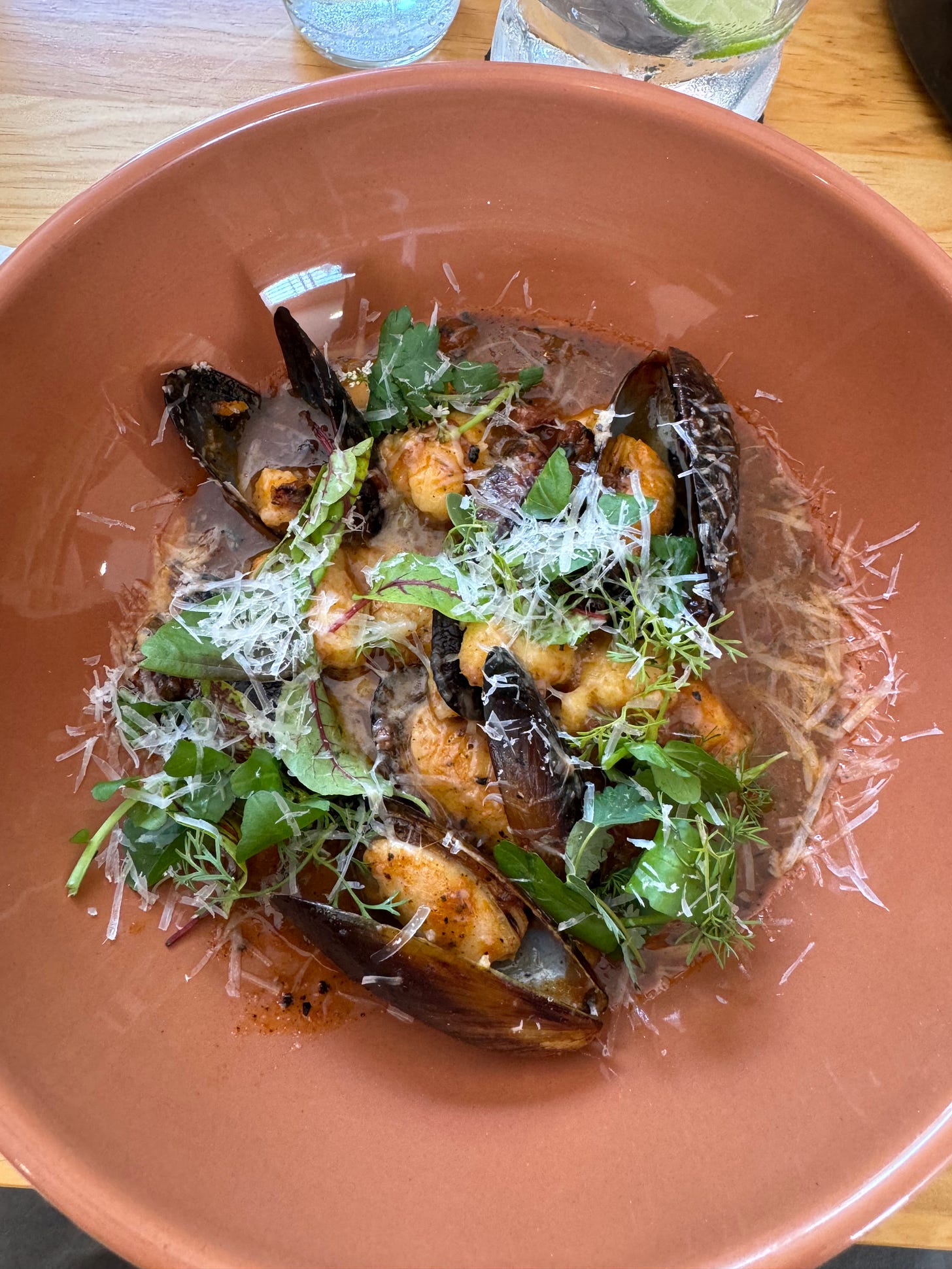 Gnocchi with greens and mussels in a round bowl.