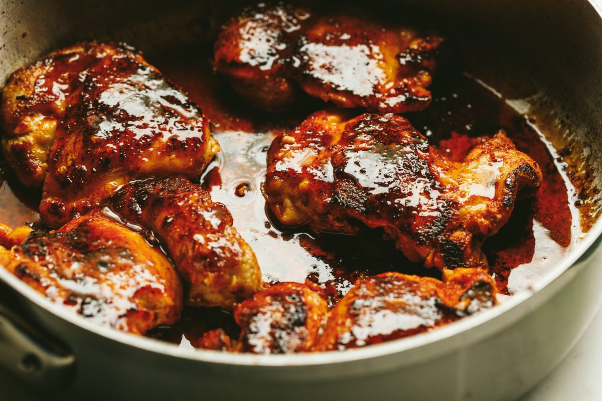 Hot honey chicken thighs in a stainless steel skillet.