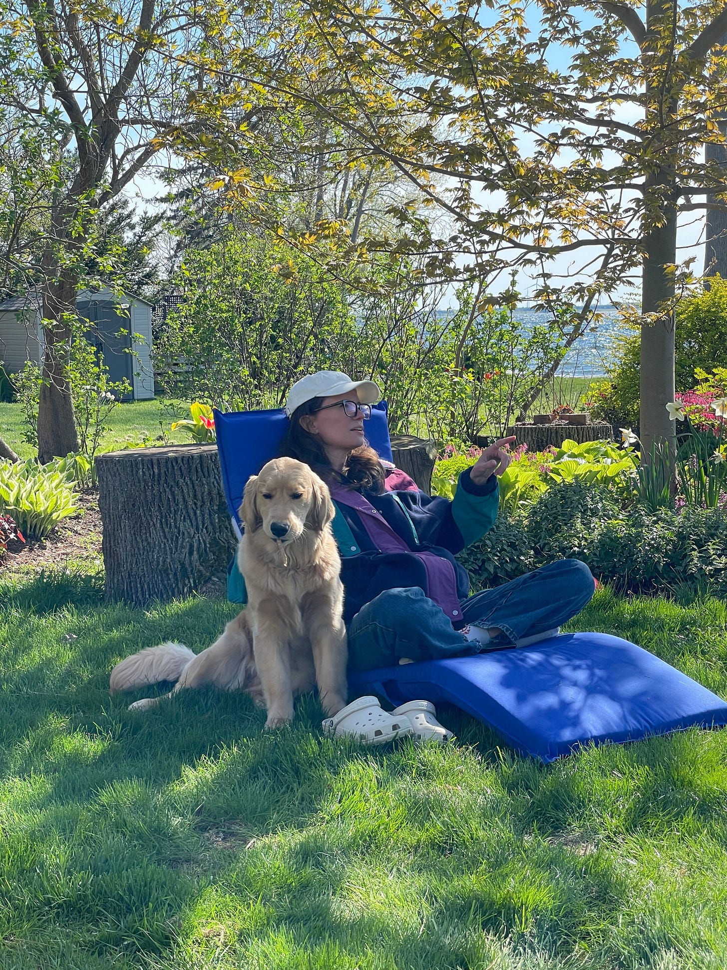 a white woman with long brown hair sits with her dog outside