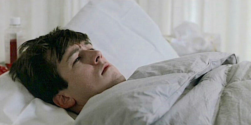Cameron from Ferris Bueller's Day Off lying in bed under his comforter.