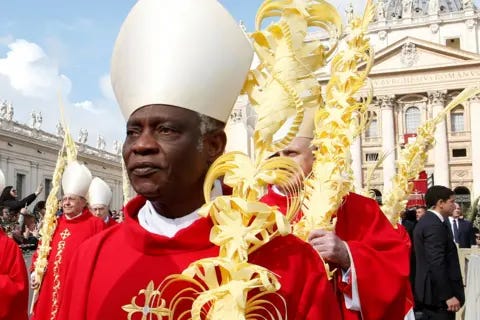 Reuters A mid-crop of Cardinal Peter Turkson looking solemnly ahead while wearing traditional religious robes along with others outside St. Peter's Basilica in April 2019. 