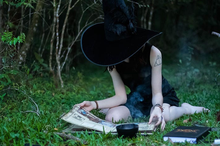 Image of a witch reading on the grass.