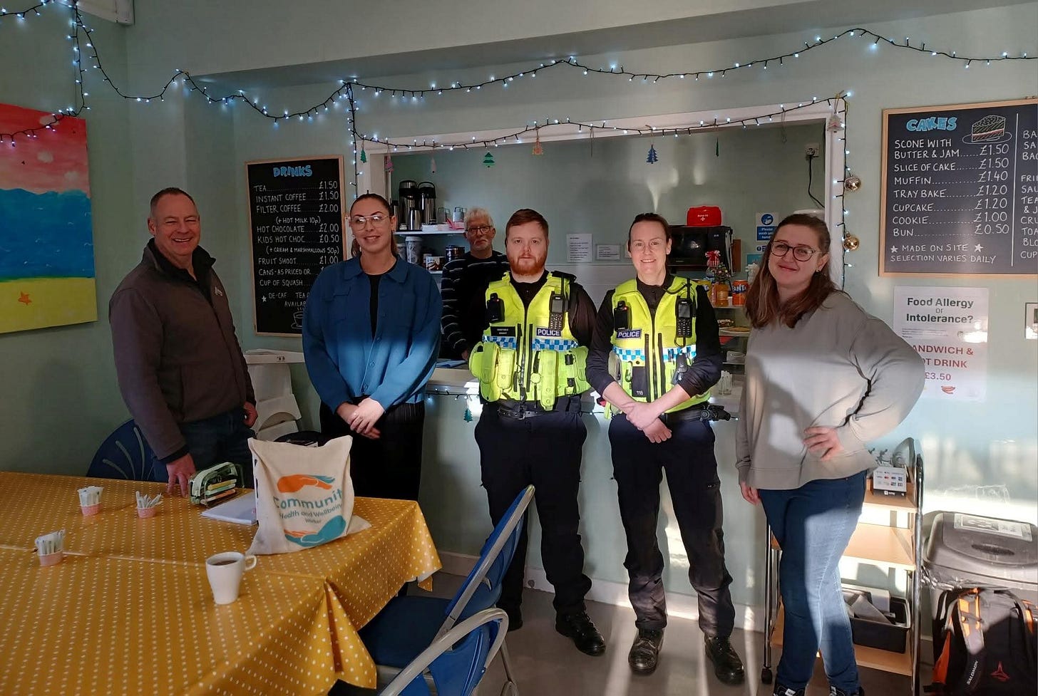Two Selby Local Police people visited Our Space to meet with volunteers and residents. They are all stood facing the camera smiling in front of the tearoom serving counter and in front of them is a cafe table with cups of tea on it. Two Selby Local Police people visited Our Space to meet with volunteers and residents. They are all stood facing the camera smiling in front of the tearoom serving counter and in front of them is a cafe table with cups of tea on it.